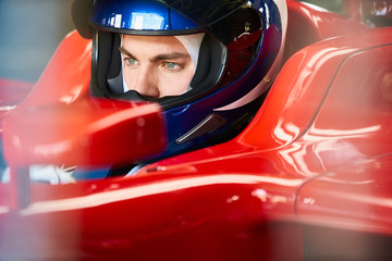 Close up focused formula one driver wearing helmet in race car