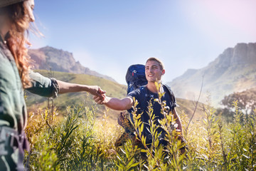 Young couple holding hands hiking in sunny valley