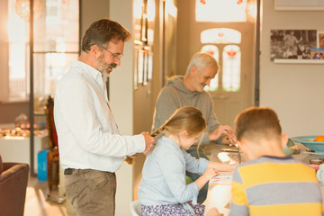 Gay father braiding daughter hair at kitchen counter