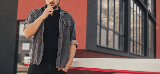Young handsome man smoke with vape in urban location