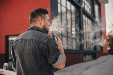 Young handsome man smoke with vape in urban location