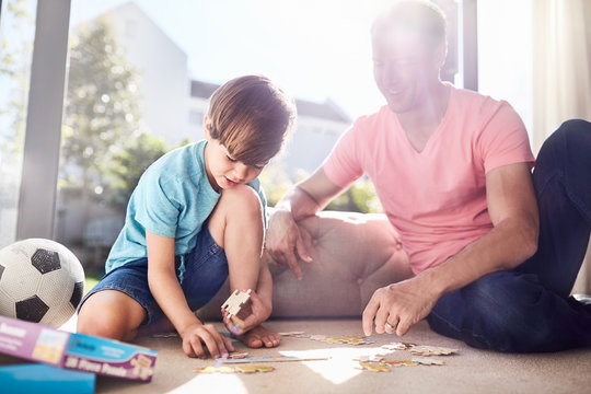 Father and son assembling jigsaw pieces on floor