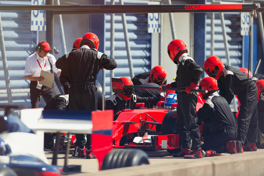 Pit crew replacing tires on formula one race car in pit lane