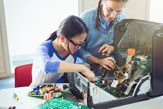 Girl students assembling computer in classroom