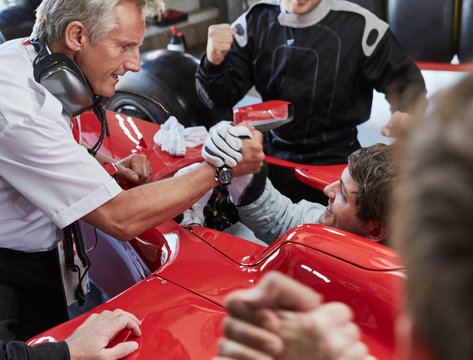 Manager formula one race car driver handshaking, celebrating victory