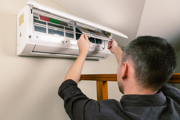 Obraz premium Male technician cleaning air conditioner indoors
