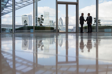 Businessmen handshaking in highrise office urban city view, London, UK