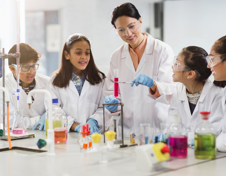 Female teacher and students conducting scientific experiment in laboratory classroom