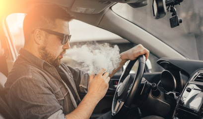 Young handsome man smoke with vape in vehicle