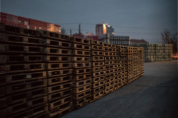 A row or stack of wooden euro palettes in early foggy morning. Used euro palettes waiting in an...