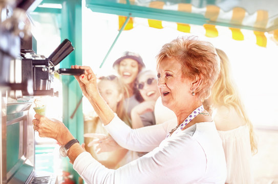 Smiling senior female business owner serving ice cream at food cart