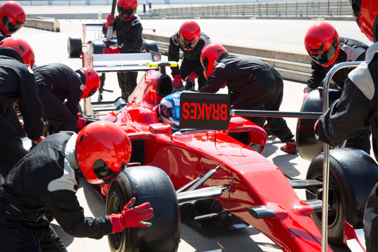Pit crew replacing tires on formula one race car in pit lane