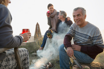 Mature couples drinking wine and barbecuing on beach
