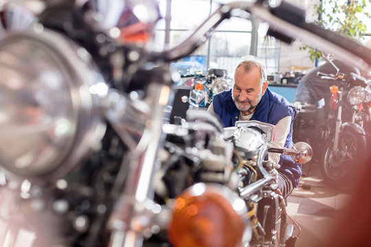 Senior male motorcycle mechanic working in shop