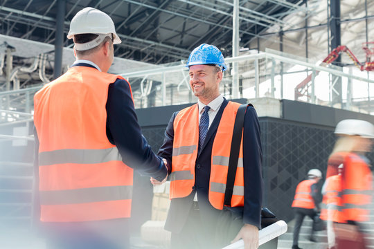 Male engineers handshaking at construction site - Powered by Adobe