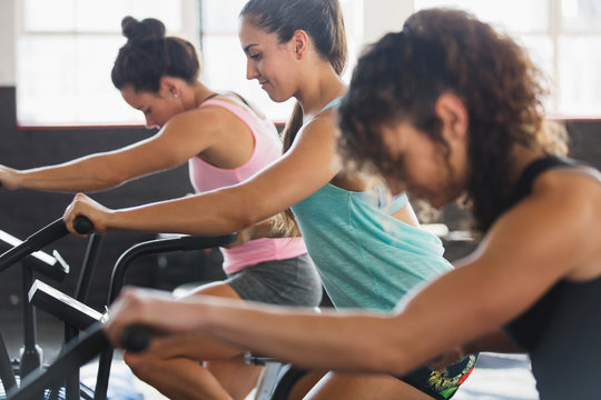 Focused young women using elliptical bikes in exercise class