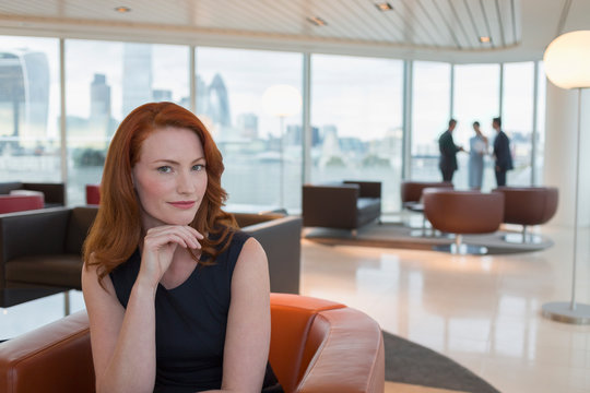 Portrait confident businesswoman red hair in urban highrise office lounge