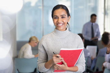 Portrait smiling businesswoman with notebook in conference audience
