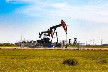 A wide angle view of two enclosed oil wells, with overground pump jacks and working gear....