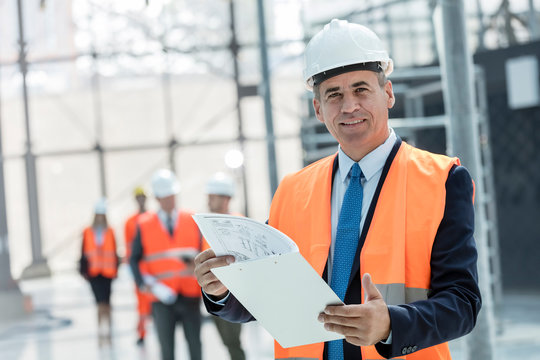 Portrait smiling businessman with clipboard at construction site