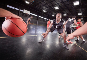 Young male basketball players playing game on court in gymnasium