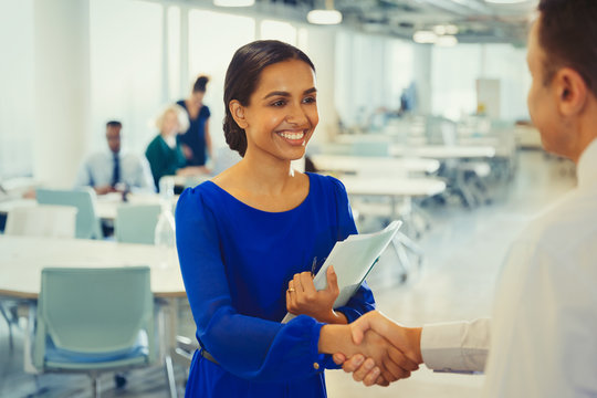 Smiling businesswoman shaking hands with businessman in office
