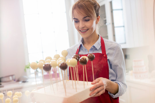 Smiling female caterer baking cake pops in kitchen