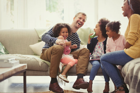 Multi-ethnic young family laughing on sofa
