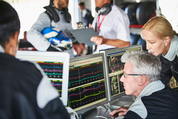 Formula one team reviewing diagnostics telemetry data on computers