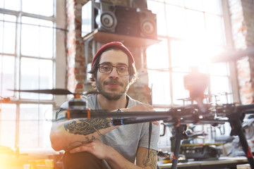 Portrait confident male designer tattoos working on drone in workshop