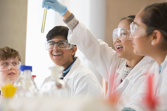 Students examining liquid in test tube, conducting scientific experiment in laboratory classroom