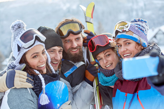 Smiling skier friends taking selfie with camera phone