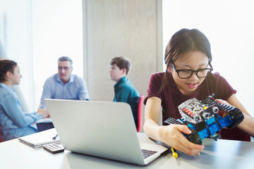 Girl student programming and assembling robotics in classroom