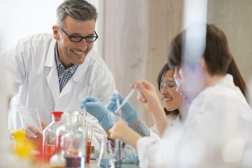 Male science teacher and students conducting scientific experiment in laboratory classroom