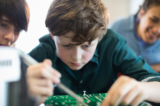 Focused boy student assembling electronics in classroom