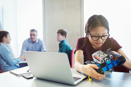 Girl student programming and assembling robotics in classroom