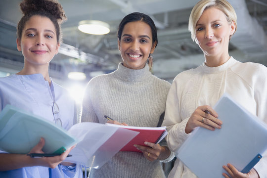 Portrait smiling, confident businesswoman with paperwork