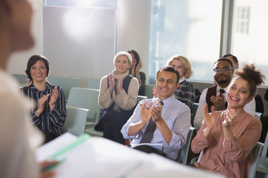 Business people in audience clapping for conference speaker