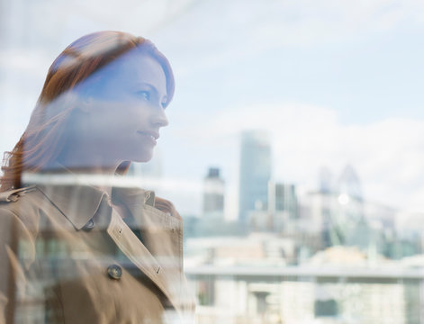 Smiling businesswoman red hair looking at city view on urban balcony