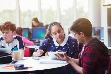 Students researching, using digital tablet at table in library