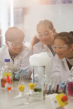 Surprised students conducting scientific experiment, watching chemical reaction in classroom laboratory