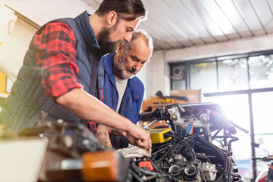 Motorcycle mechanics repairing motorcycle in workshop