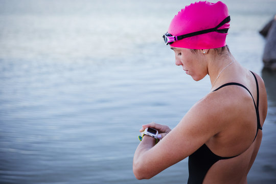 Female open water swimmer checking smart watch at ocean