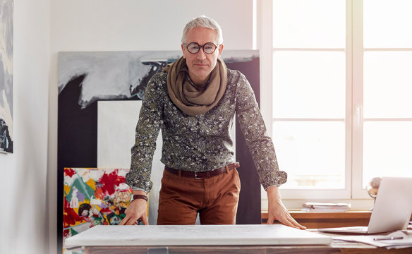 Portrait confident male photographer standing over canvas in art studio
