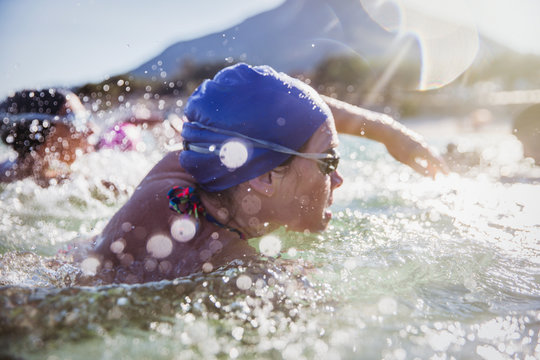 Determined female open water swimmer swimming in sunny ocean