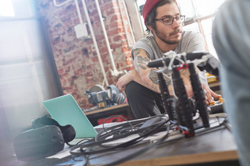 Male computer programmer programming electronics in workshop