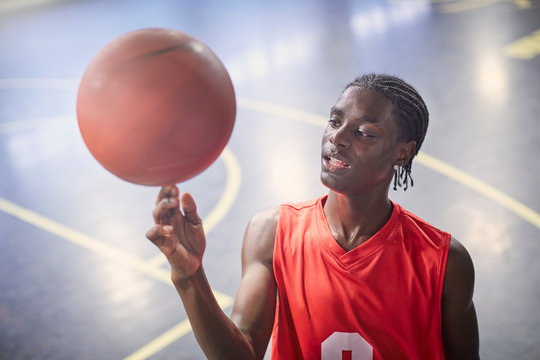 Young male basketball player spinning basketball on court