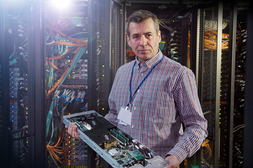 Portrait male IT technician holding panel in server room