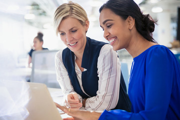 Smiling businesswomen using laptop