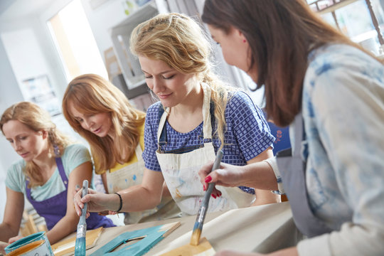 Female artists painting picture frames in art class workshop